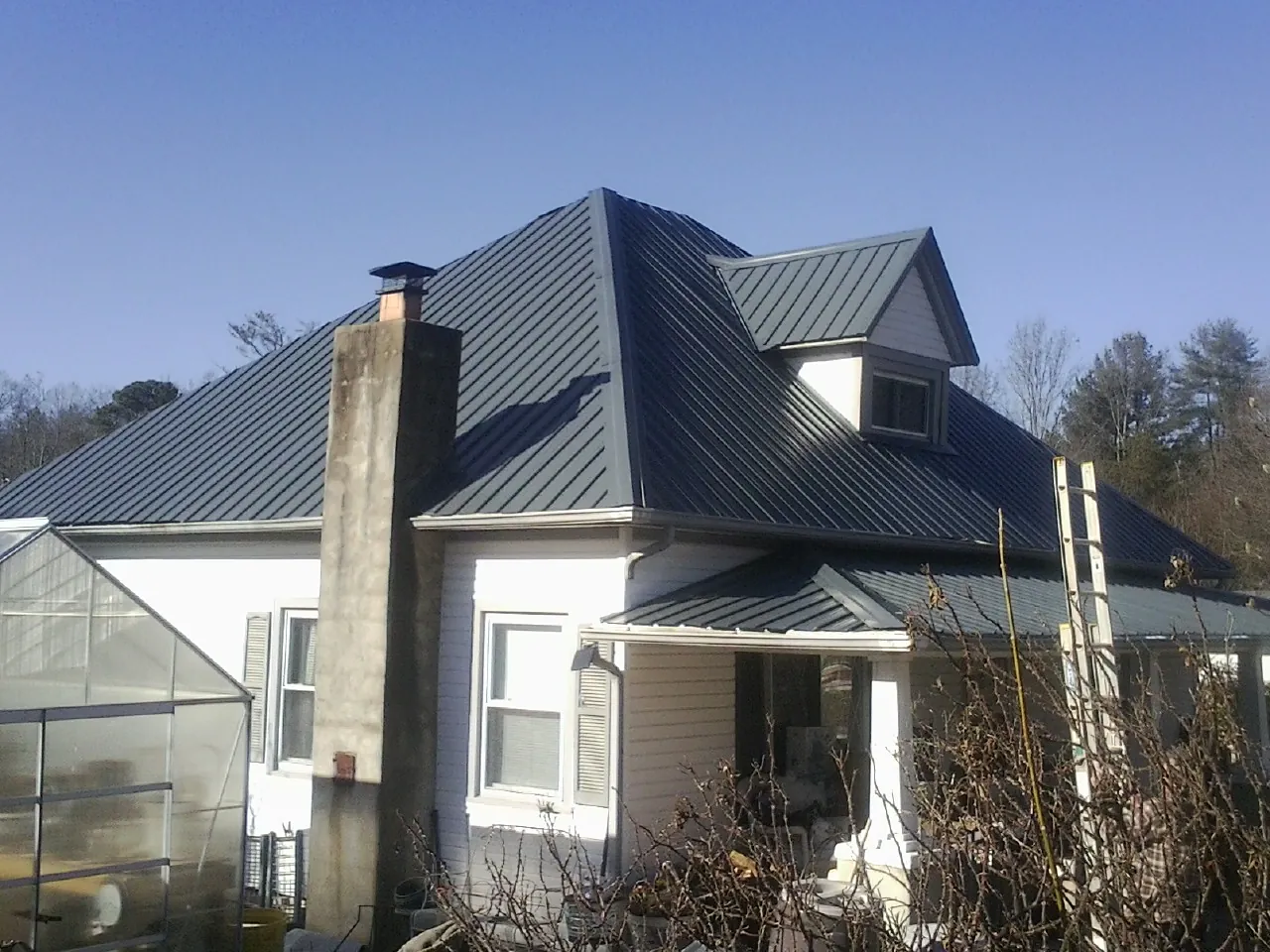 Dark blue standing seam metal roof on a white farmhouse with dormer — Slate & Tile Roof Repair by Roofing Brothers in Klamath River