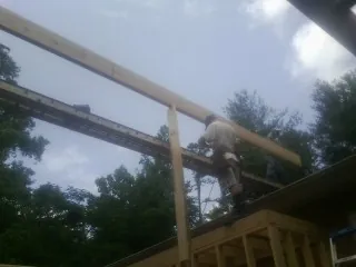 Carpenter setting a ridge beam over a new addition frame — Ice Dam Removal by Roofing Brothers in Klamath River