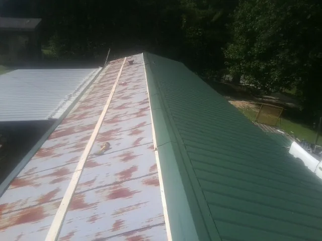 Old rusted panels beside newly installed green metal roofing — Wind Damage Roof Repair by Roofing Brothers in Klamath River