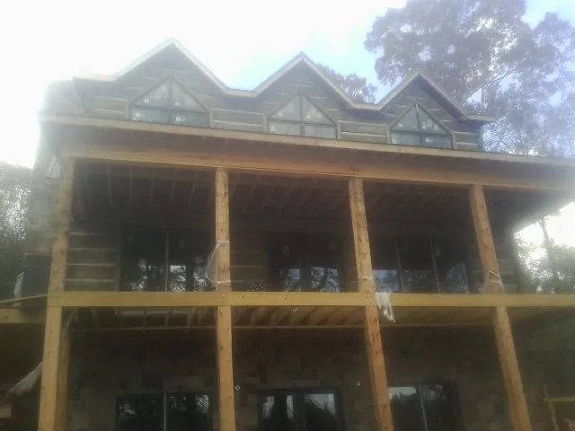 Dormers and porch framing on a large log home under construction — Roof Coating work by our crew in Klamath River