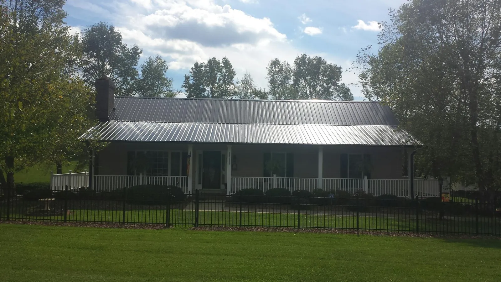 Gray metal roof on a brick ranch with a full width front porch — Gutter Guard Installation work by our crew in Klamath River