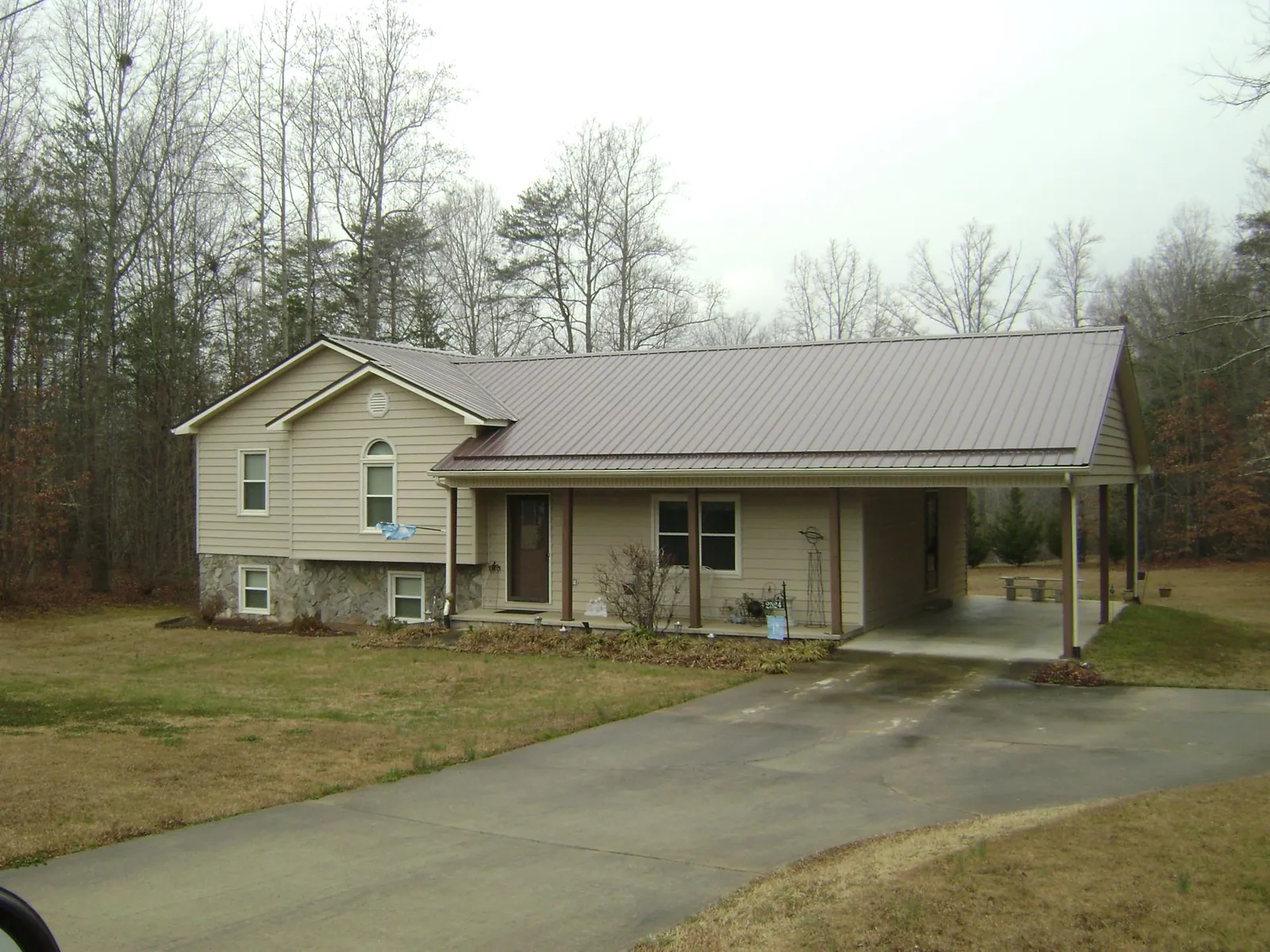 Brown metal roof on a tan split level home with an attached carport in Klamath River