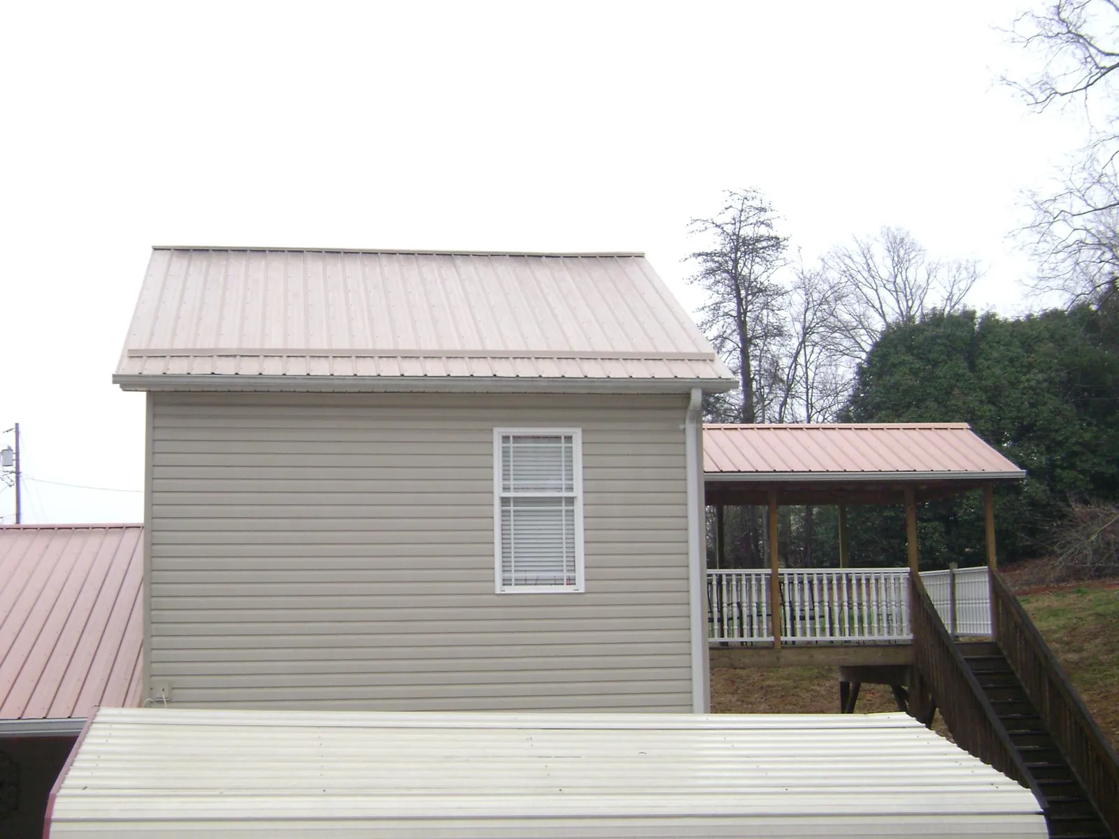 Tan metal roofs on a two story addition and attached porch, from a Roof Replacement job in Klamath River