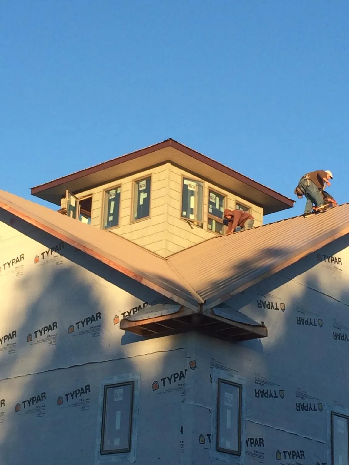 Roofers working around a rooftop cupola on a new metal roof at sunset — Roof Waterproofing in Klamath River by Roofing Brothers